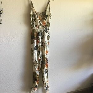 Jumpsuit in a white background and floral. Bottom sides opening with ties